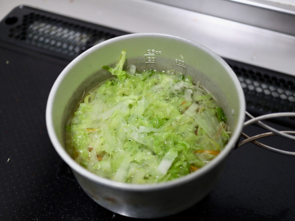 クッカーに山盛りのカットキャベツを入れて家で味噌汁を作る様子