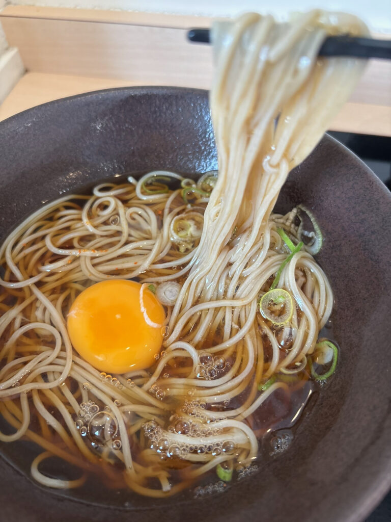 箸で持ち上げたゆで太郎の細切り蕎麦と生たまご
