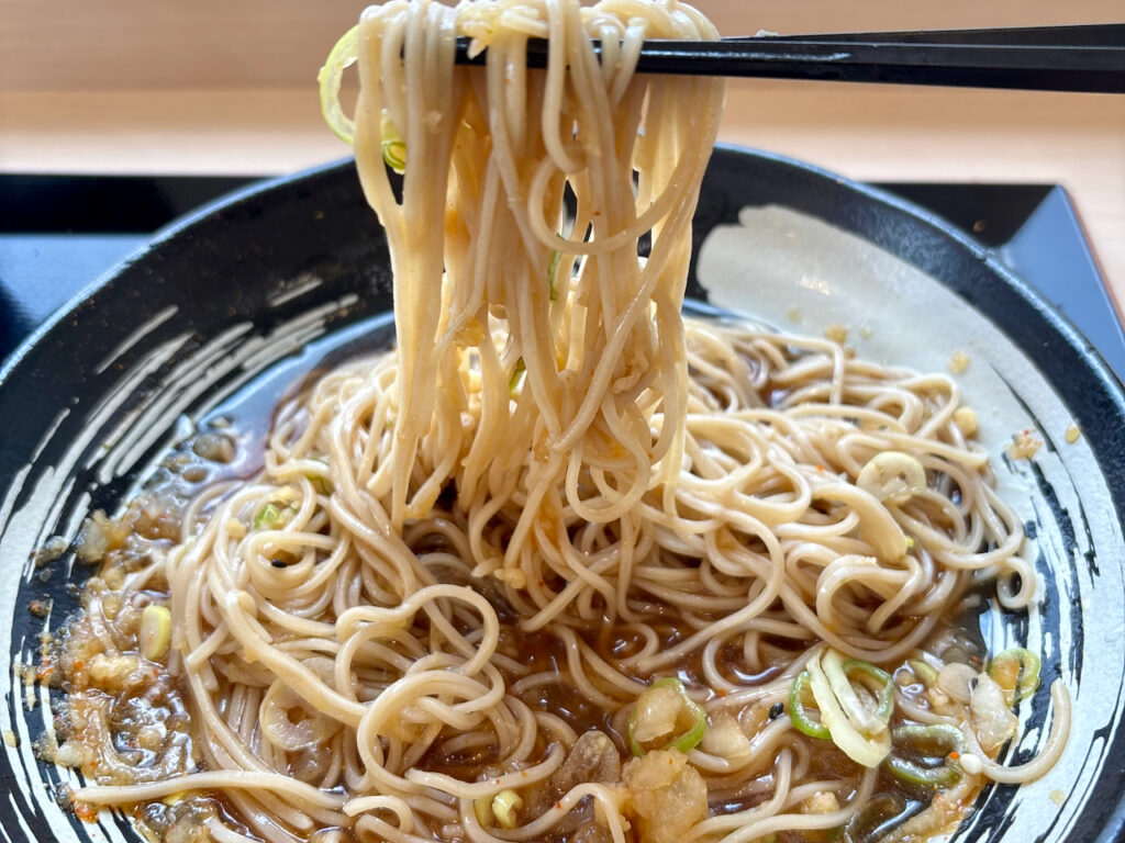 ごちゃまぜにした鬼おろしとおつゆがよく絡むそばを箸で持ち上げた様子
