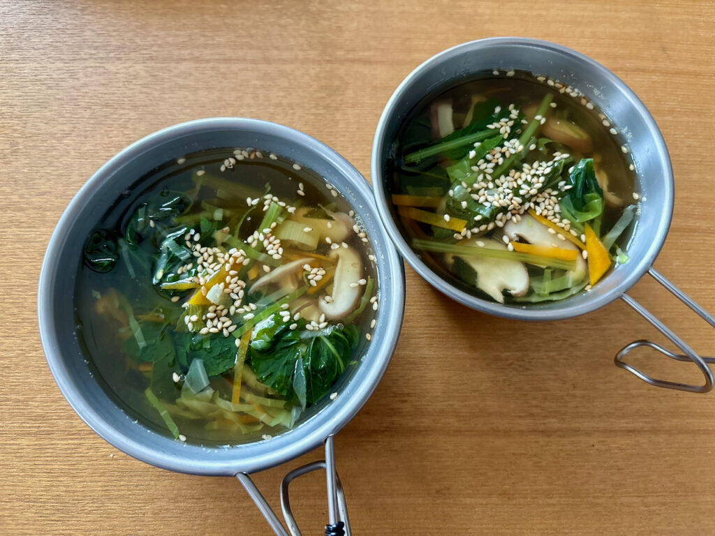 シェラカップに入った具だくさんの温かい野菜とキノコのスープ