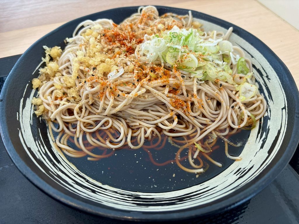 蕎麦の上にねぎ、天かす、すりごま、七味、赤鬼をトッピングした状態