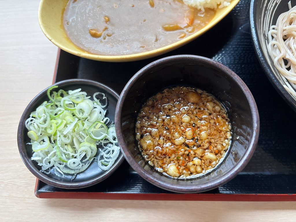 カウンターの揚げ玉と七味を投入した特製そばつゆ